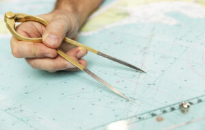 The-Captain-Measures-The-Dista-346234711-300x190 The Captain Measures The Distance On The Map With A Compass. Clo
